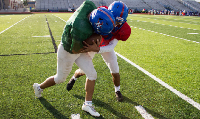 Senior Cornerback Hector Fuentes and junior Quarter- back Xavier Martinez reenact an illegal move, spearing, after their varsity practice. In an actual game, a corner- back would go after the quarterback and try to tackle to stop the play. Photo by Mya Tapia.